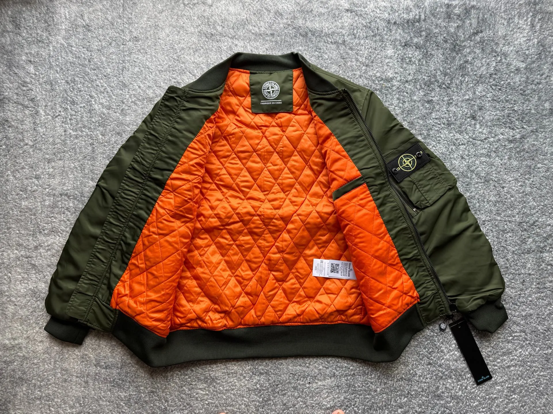 P360 Stone lsland Stone Island Medal Aviator Cotton Jacket The outer fabric is made of MA-1 flight nylon, which is a material specially used in flight and aviation. Flying nylon is a fabric specially used in flight and aviation. It is rarely used in ordinary clothing. The density of flying nylon is very high, so it is windproof and waterproof. When rain falls on the surface of the clothes, it will not penetrate immediately, but will form a small water droplet and slide off. This performance is a requirement for the development of modern jet technology. Because it is assumed that the pilot got caught in the rain before getting on the plane, he entered the cabin covered in rainwater. When flying at high altitude and at high speed, in a cabin without an environmental control system, water droplets will freeze on the pilot's body 2. Knitted baseball collar MA-1 uses a knitted collar. The collar is made of wool and can be snug around the neck and very warm. 3. Metal zippers We have very strict requirements on zippers, including smoothness and size. There was no zipper on the market that met the requirements, so we asked a zipper factory to customize a strong and durable metal zipper.  4. Double-threaded knitted cuffs The cuffs are made of double-threaded knitted fabric, narrow at the front and wide at the back. The narrow part can be tightened around the wrist to prevent wind from entering. The wide part has enough space when wearing multiple pieces under winter Color: Black Dark Army Green Size: M L.
